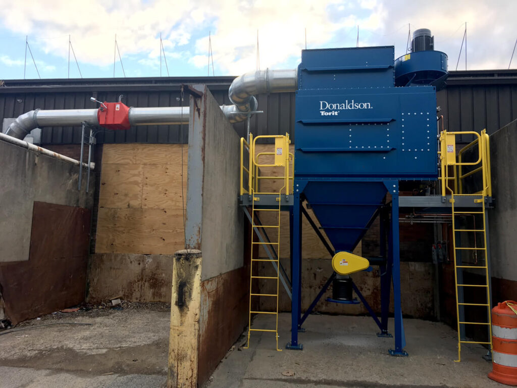 A blue Donaldson dust collector outside a plant