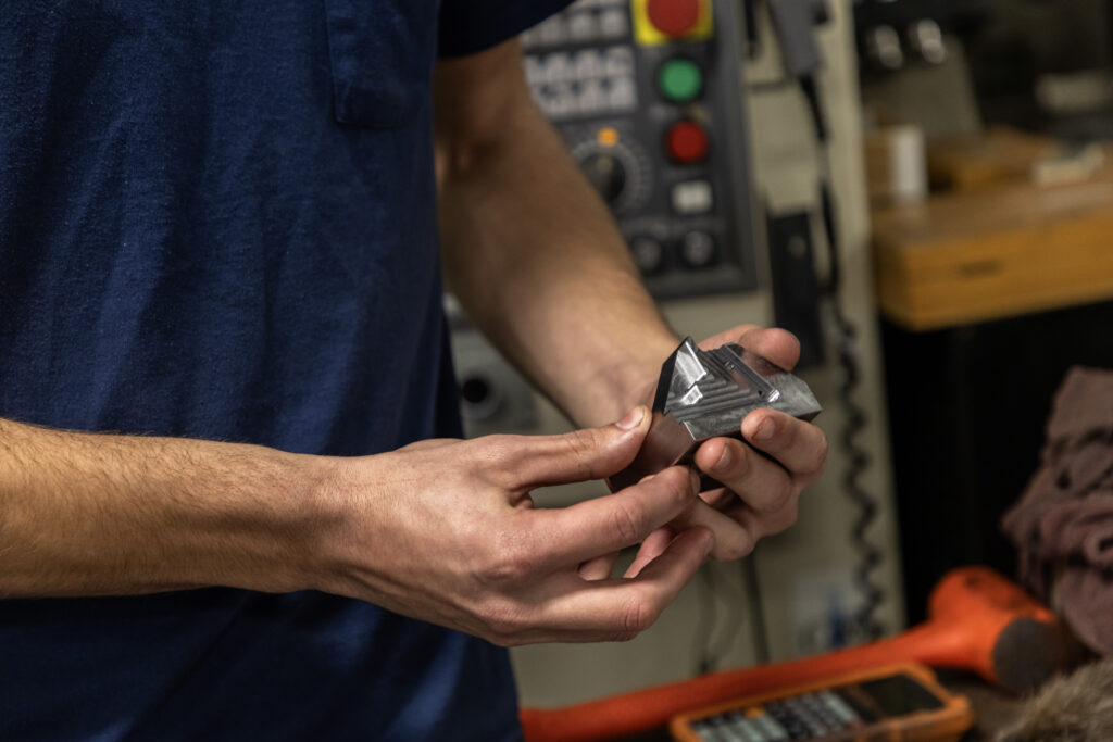 A person holds a small, machined metal component.