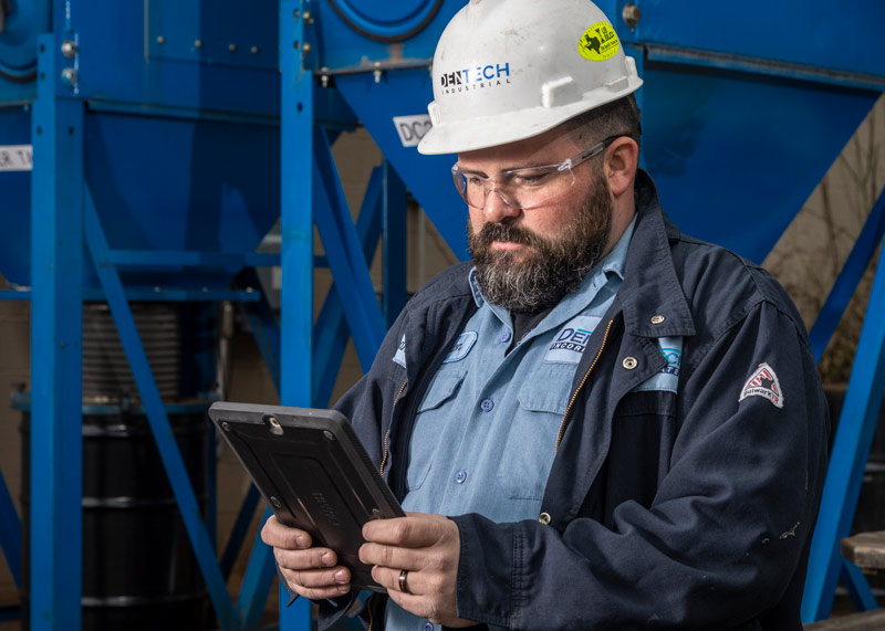 A DenTech service technician reviews inspection information on a mobile tablet.